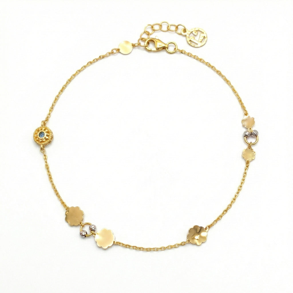 Gold anklet with various shaped gold beads on a white background