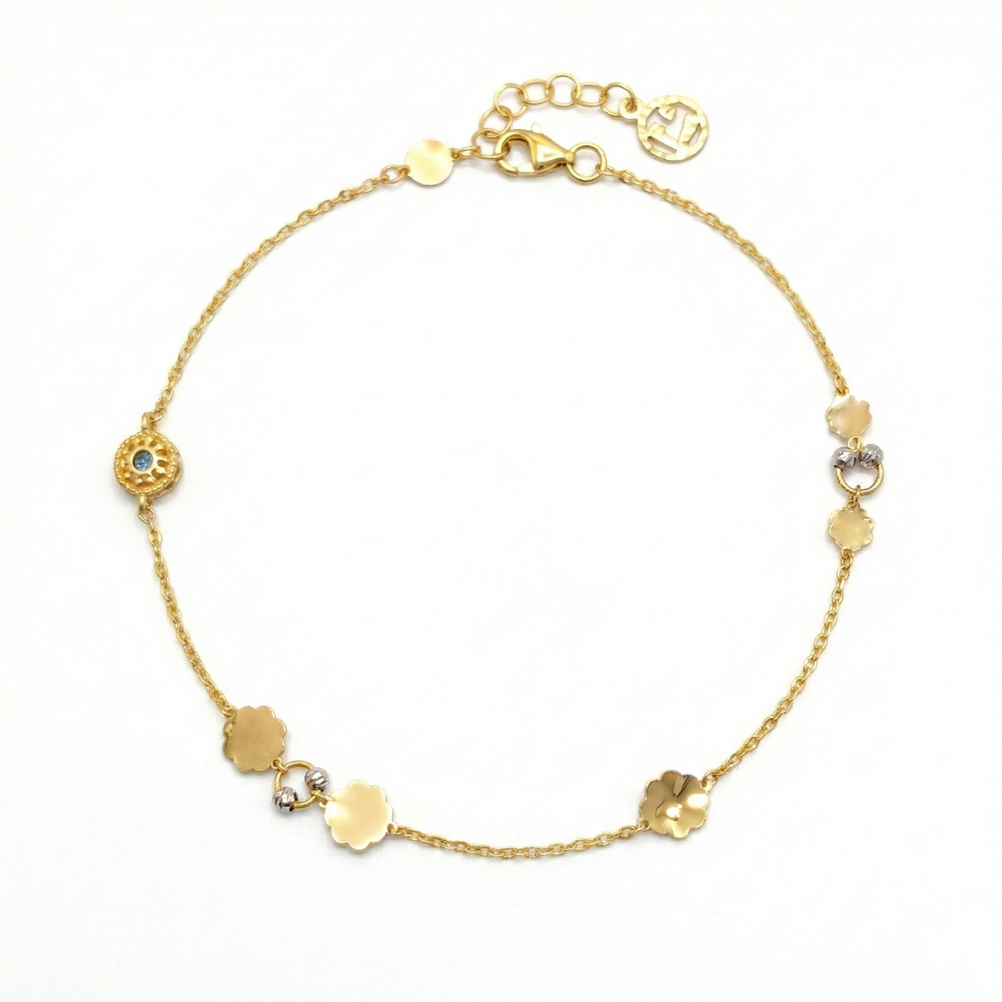 Gold anklet with various shaped gold beads on a white background