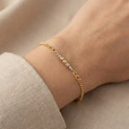 Gold bracelet on a wrist with a neutral background