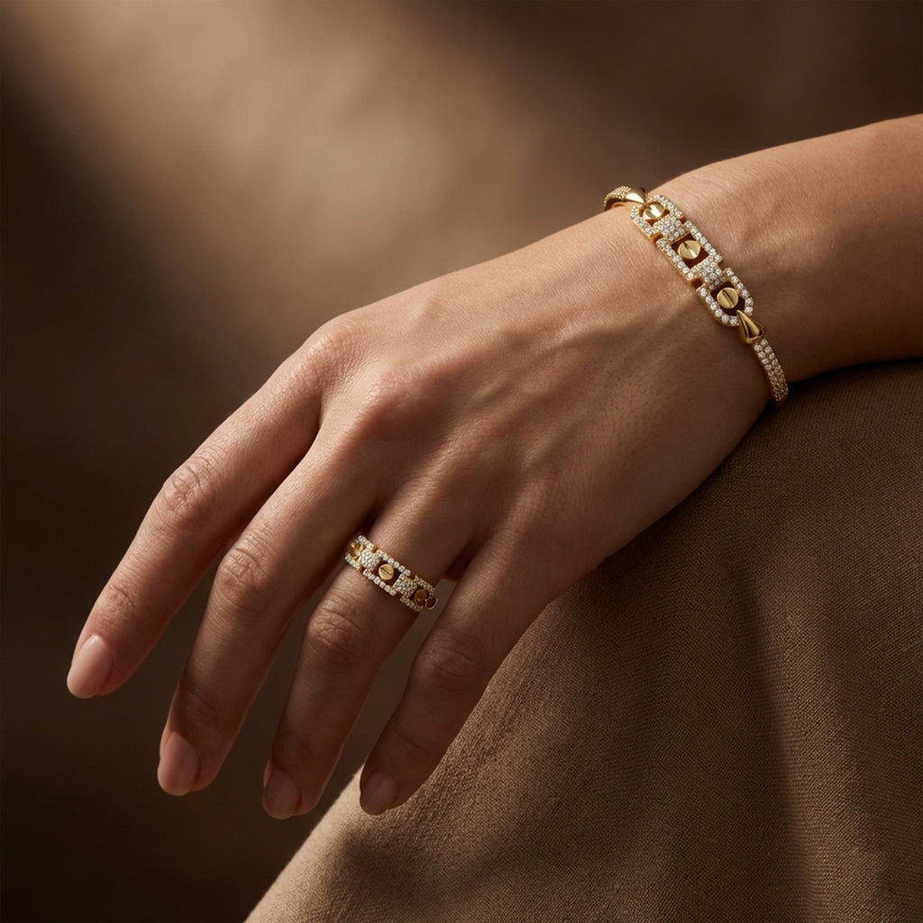 Gold bracelet and ring on a hand against a brown background