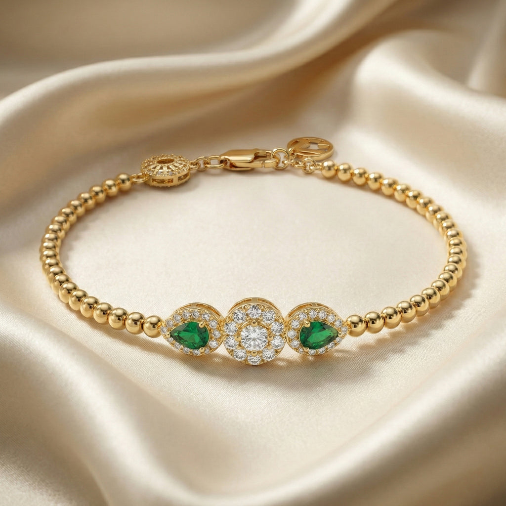 Gold bracelet with green gemstones and a diamond on a beige fabric background