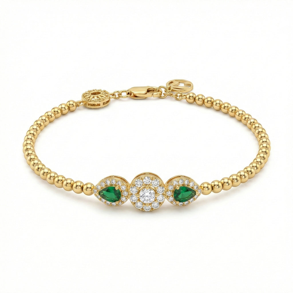 Gold bracelet with emerald and diamond accents on a white background