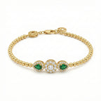 Gold bracelet with emerald and diamond accents on a white background