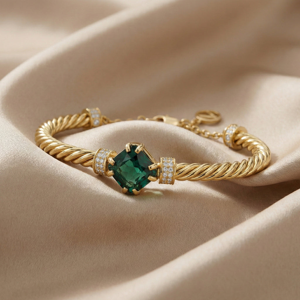 Gold bracelet with a green gemstone on a beige fabric background