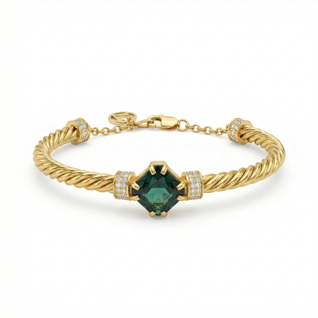 Gold bracelet with a green gemstone on a white background
