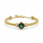 Gold bracelet with a green gemstone on a white background
