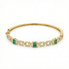 Gold bracelet with emerald and diamond accents on a white background