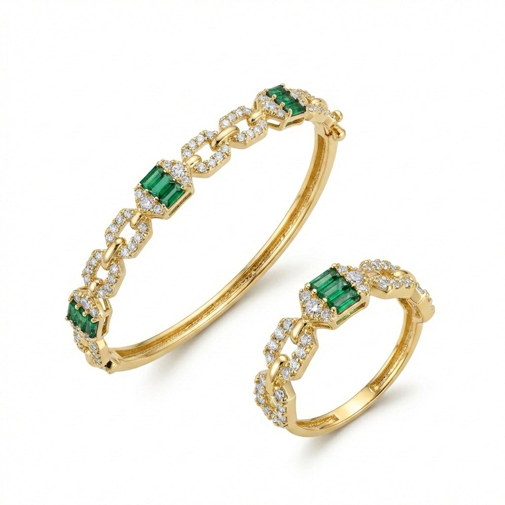Gold bracelet and ring set with emeralds and diamonds on a white background