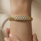 Macro view of the Lazurde 18k yellow gold bracelet centerpiece on a wrist. The shot emphasizes the high-polish woven texture of the gold and the sharp, brilliant reflections of the pave-set stone arrangement.