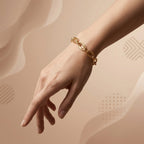 Editorial lifestyle shot of the Dreams 18k yellow gold bracelet on a feminine wrist against a nude beige background.