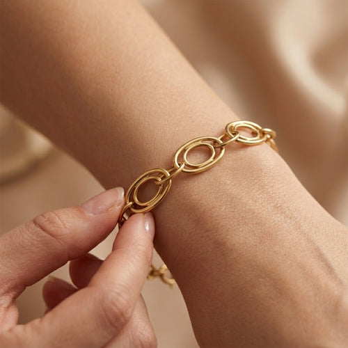 Luxury close-up of the Dreams 18k yellow gold bracelet being gently touched on a wrist.