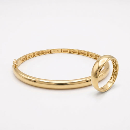 Matching L'azurde 18k yellow gold set including a polished bangle and a tapered ring, isolated on a pure white background.
طقم لازوردي من الذهب الأصفر عيار 18 يضم إسورة مصقولة وخاتم مطابق مسحوب، معزول على خلفية بيضاء نقية.