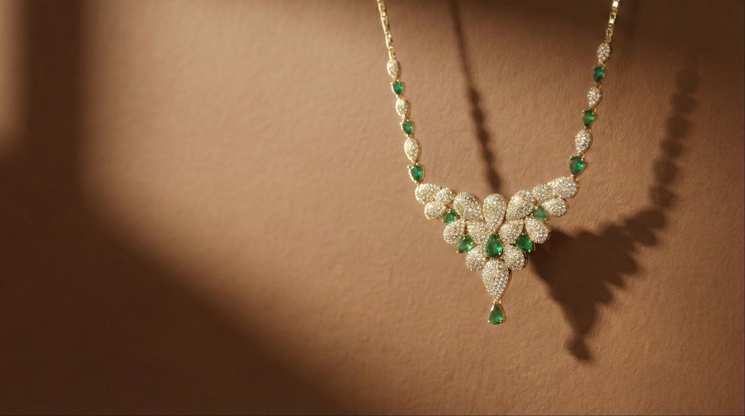 Delicate necklace with green and clear gemstones on a brown background