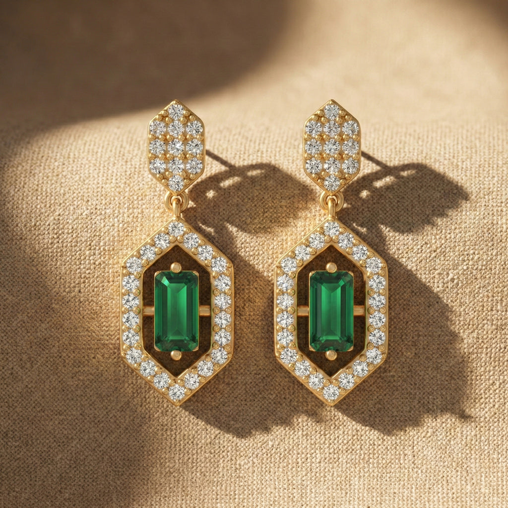 Gold earrings with green gemstones on a beige fabric background
