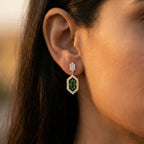 Close-up of an ear wearing a green gemstone earring with a blurred background