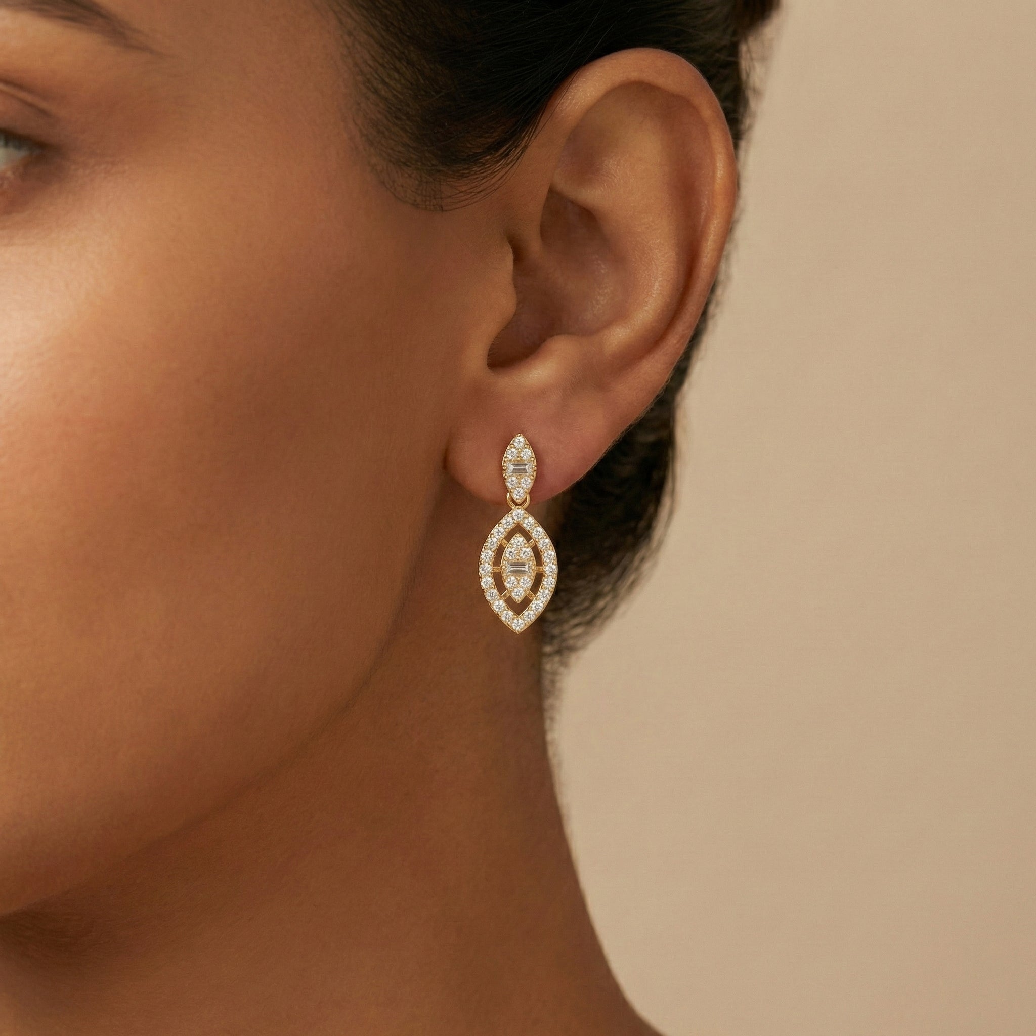 Close-up of a woman wearing a diamond earring against a beige background