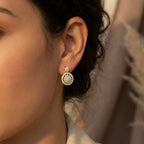 Close-up of a person wearing a diamond earring with a blurred background