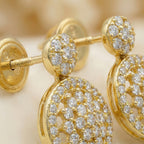 Gold earrings with diamond accents on a beige background