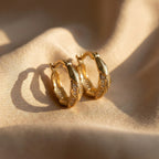 Gold hoop earrings on a beige fabric background