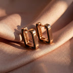 Gold hoop earrings on a soft pink fabric background