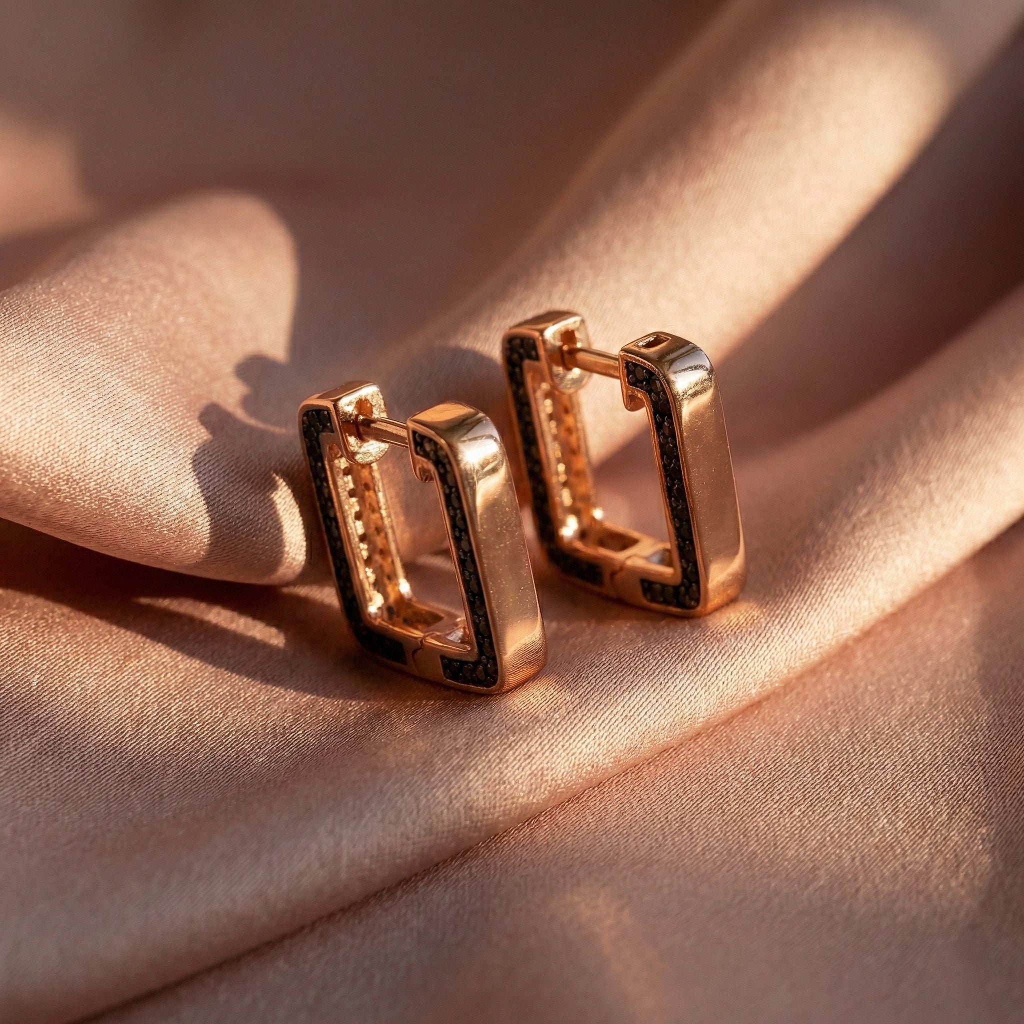 Gold hoop earrings on a soft pink fabric background