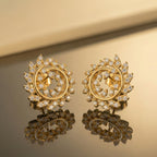Pair of gold earrings with diamond accents on a reflective surface.