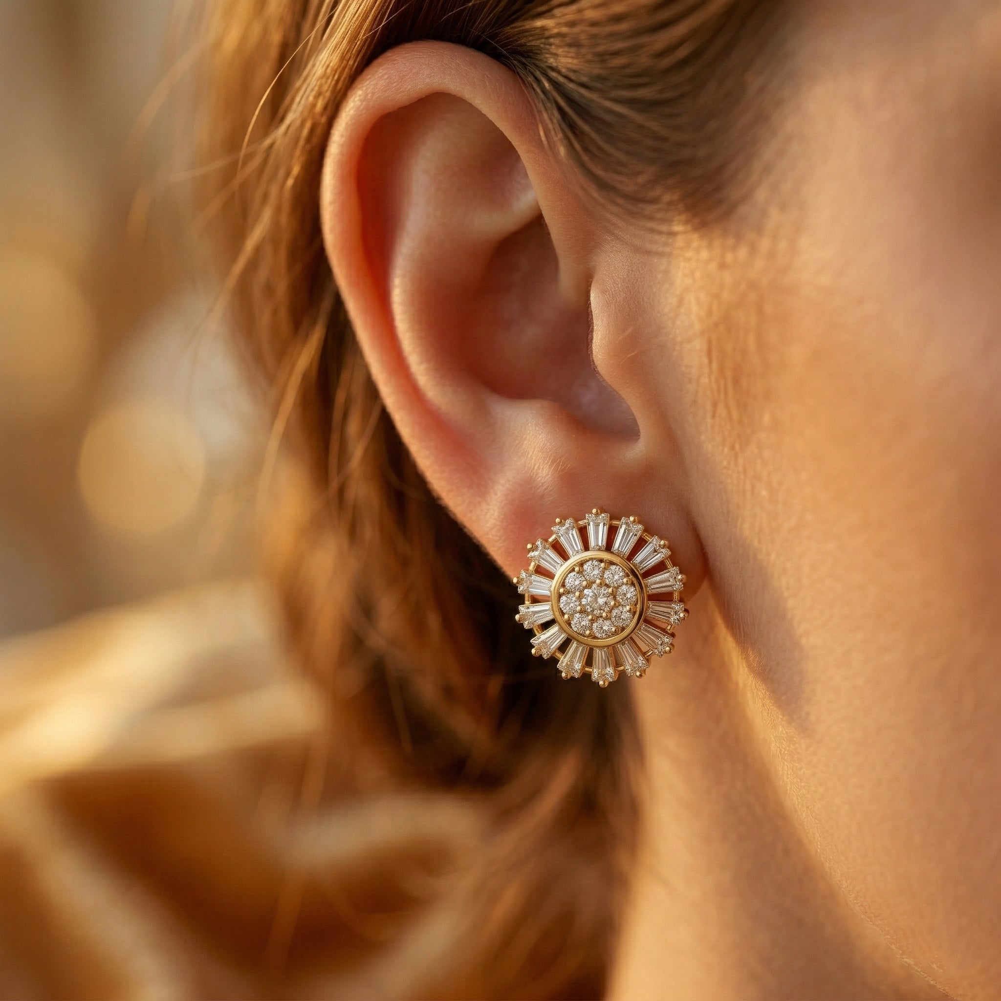 A luxurious close-up profile shot of a person wearing a Lazurde 18k yellow gold sunburst stud earring. Soft, warm lighting gently illuminates the baguette and round stones against a blurred background.