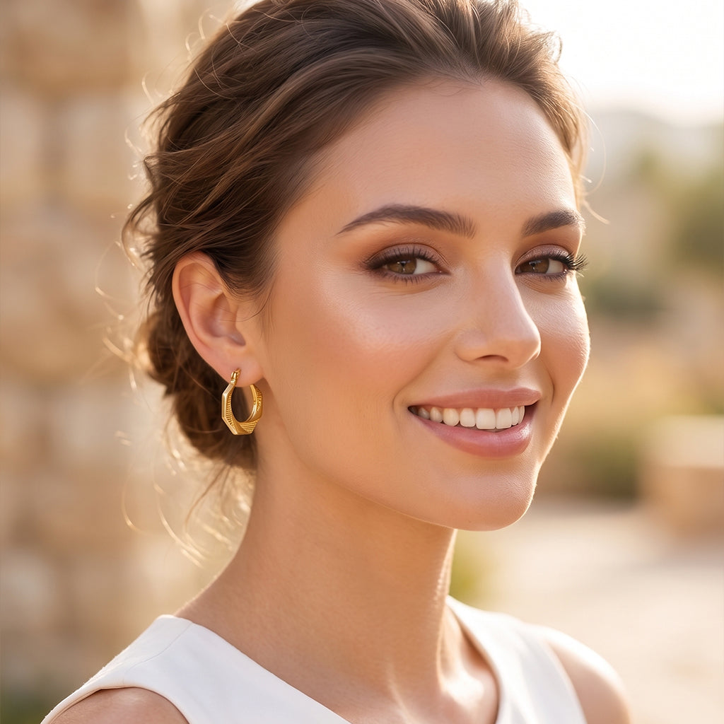 Elegant woman smiling naturally while wearing Royal Select 18k yellow gold geometric hoop earrings weighing 3.47 gm, styled outdoors in soft natural sunlight.
شابة أنيقة ومبتسمة لابسة حلق هندسي من رويال سيلكت (Royal Select) دهب أصفر عيار 18 بوزن 3.47 جرام، متصورة بره في إضاءة الشمس الطبيعية الناعمة.