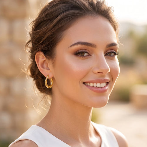 Elegant woman smiling naturally while wearing Royal Select 18k yellow gold geometric hoop earrings weighing 3.47 gm, styled outdoors in soft natural sunlight.
شابة أنيقة ومبتسمة لابسة حلق هندسي من رويال سيلكت (Royal Select) دهب أصفر عيار 18 بوزن 3.47 جرام، متصورة بره في إضاءة الشمس الطبيعية الناعمة.