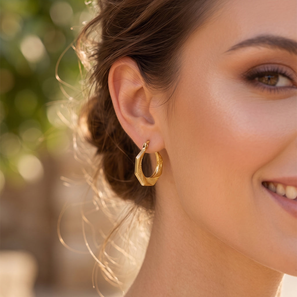 Extreme close-up of Royal Select 18k yellow gold hexagonal hoop earrings weighing 3.47 gm on a model's ear, highlighting the detailed dotted texture, sharp edges, and polished finish.
لقطة قريبة جداً لحلق سداسي من رويال سيلكت (Royal Select) دهب أصفر عيار 18 بوزن 3.47 جرام على ودن العارضة، بتبرز تفاصيل النقشة الدقيقة واللمعة بتاعت الدهب.
