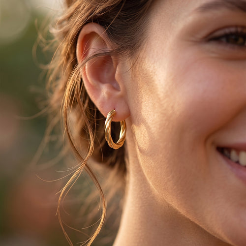 Extreme close-up of a woman's ear and jawline showcasing the craftsmanship of 18k yellow gold twisted hoop earrings in soft golden sunlight.
صورة قريبة لودن بنت بتبين دقة تفاصيل حلق دهب أصفر مجدول عيار 18 تحت إضاءة الشمس الذهبية الناعمة.