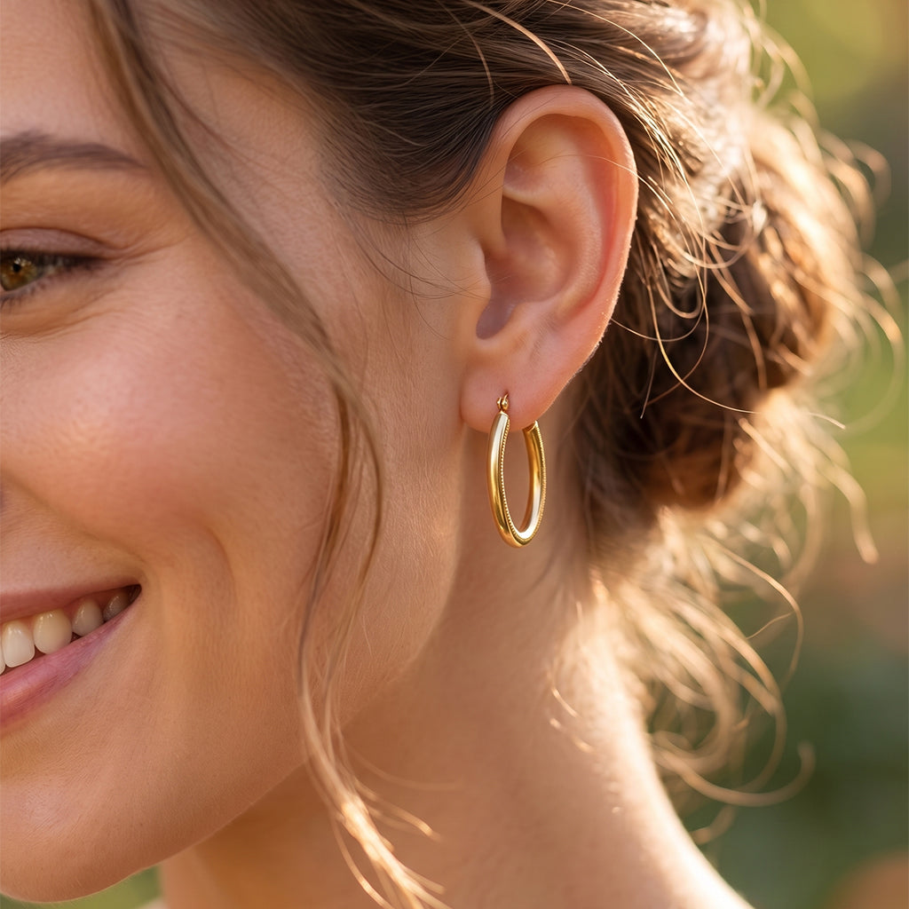 Extreme close-up of a smiling woman showcasing the polished texture of 18k yellow gold hoop earrings.
صورة قريبة جداً لودن بنت بتضحك بتبرز لمعان وتفاصيل حلق ذهب عيار 18.