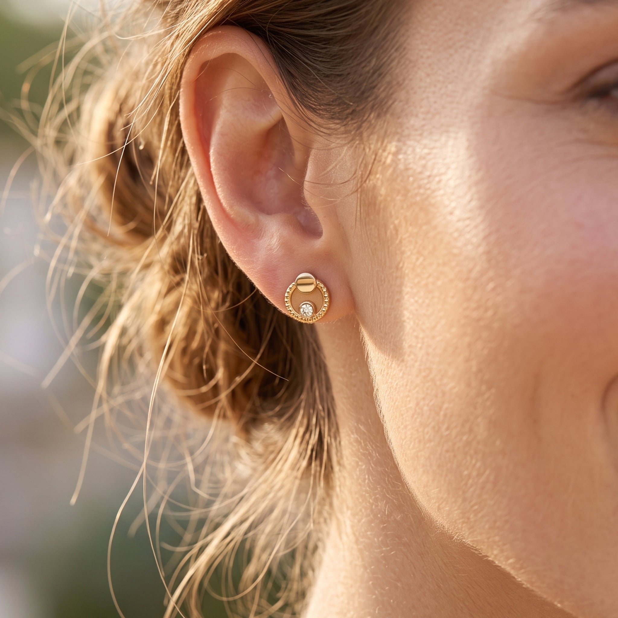 Extreme close-up of a smiling model wearing a delicate King Gold 18k yellow gold twisted halo stud earring.
تصوير ماكرو قريب لحلق بريمة دهب عيار 18 بتصميم مجدول من كينج جولد على موديل مبتسمة
