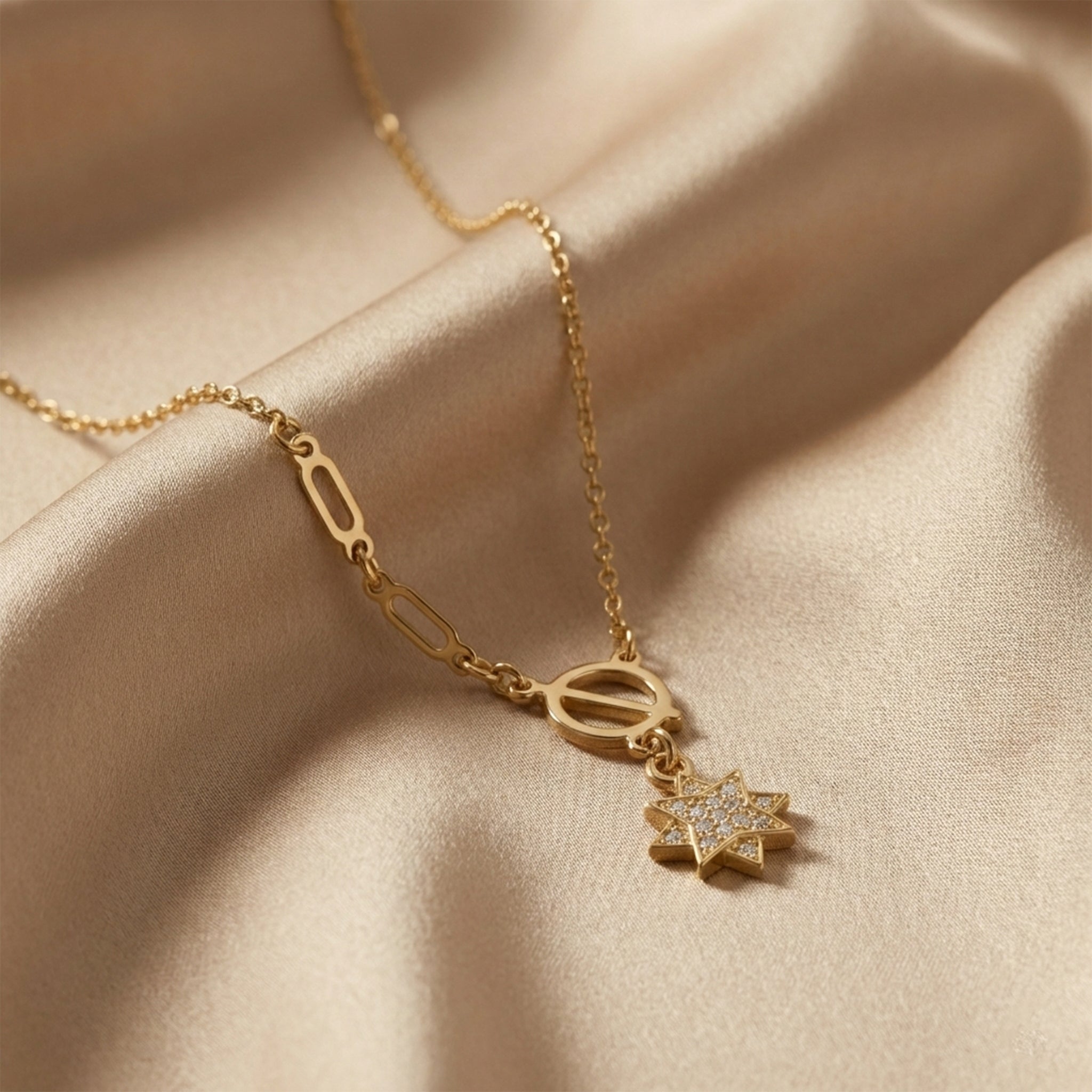 Gold necklace with star-shaped pendant on a beige fabric background