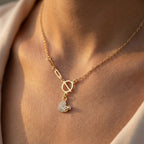 Gold necklace with a heart-shaped pendant on a person's neck