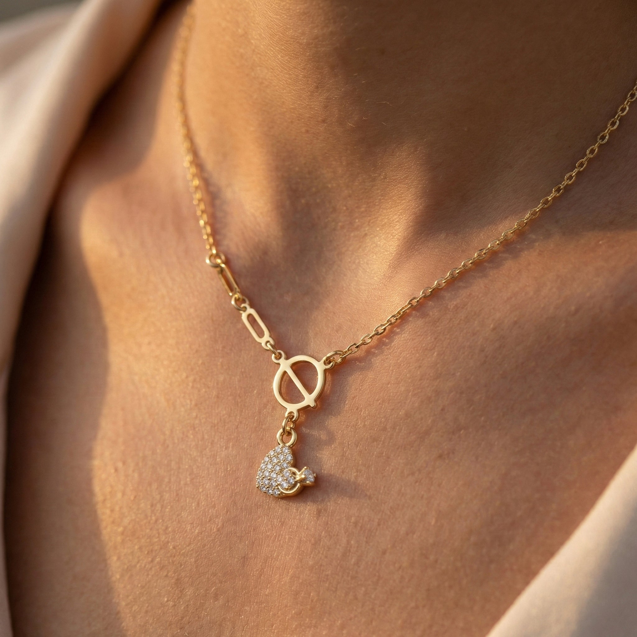 Gold necklace with a heart-shaped pendant on a person's neck