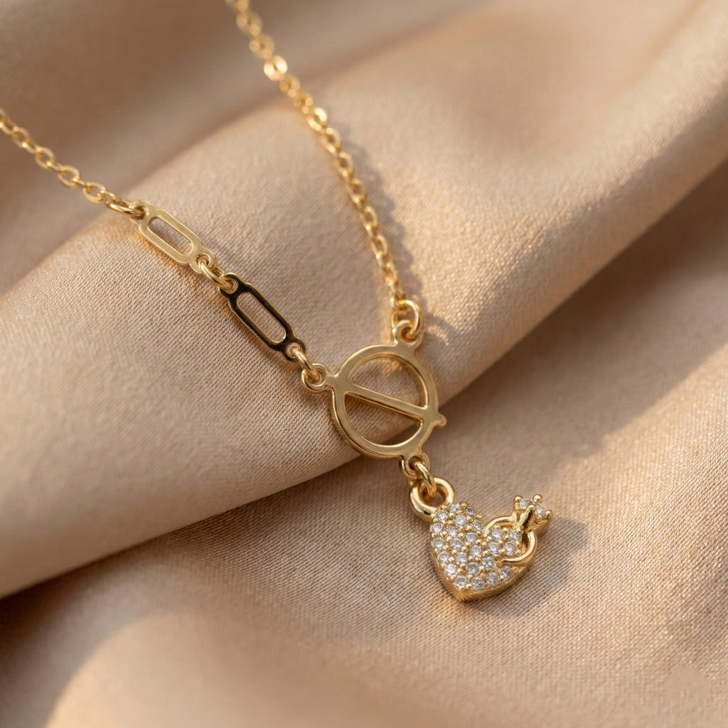 Gold necklace with a heart-shaped pendant on a beige fabric background