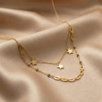 Gold necklace with star pendants on a beige fabric background