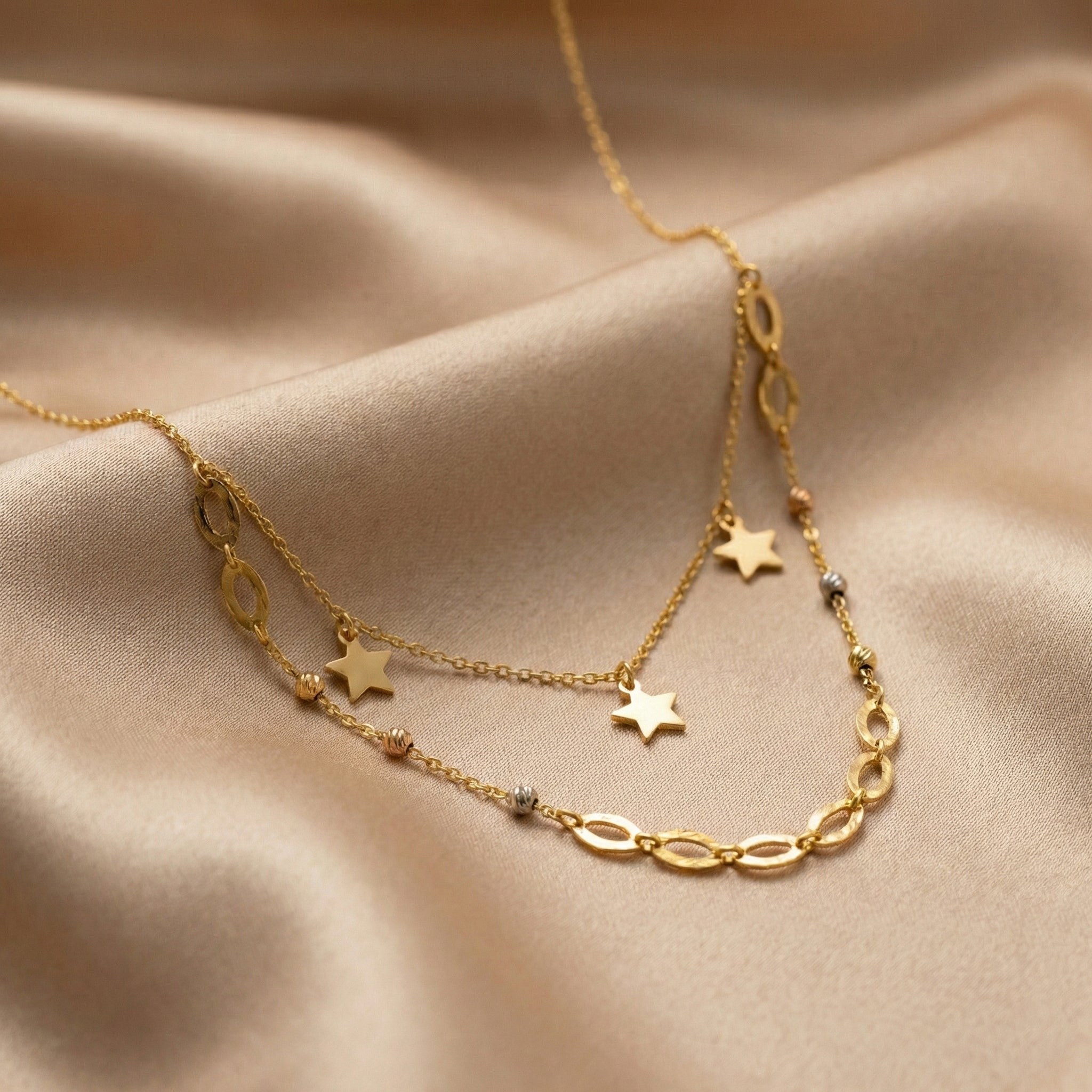 Gold necklace with star pendants on a beige fabric background