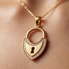 Extreme close-up of a King gold 18k yellow gold padlock pendant weighing 3.11 gm resting on a model's glowing skin, highlighting fine sparkling stones and premium craftsmanship.
لقطة مقربة جداً لقلادة قفل من كينج جولد (King gold) من الذهب الأصفر عيار 18 بوزن 3.11 جرام تستقر على بشرة العارضة، تبرز دقة التفاصيل ولمعان الفصوص والحرفية العالية.