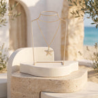 High-end 18k yellow gold starfish necklace by Remas Gold displayed on an elegant travertine pedestal against a soft Mediterranean summer background.
عرض فخم لسلسلة نجمة البحر دهب عيار 18 من ريماس جولد على قاعدة حجرية بخلفية صيفية من البحر المتوسط.