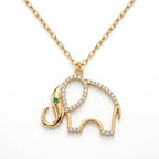 A professional studio shot of a gold necklace with an openwork elephant pendant, isolated against a solid white background. The elephant's curved back is paved with small sparkling diamonds, and its eye is a tiny green emerald.
لقطة استوديو احترافية لقلادة ذهبية مع دلاية مفرغة على شكل فيل، معزولة على خلفية بيضاء سادة. يزدان منحنى ظهر الفيل بقطع ألماس صغيرة براقة، وعينه عبارة عن زمردة خضراء صغيرة.