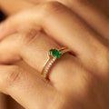 Gold ring with a green gemstone on a person's finger