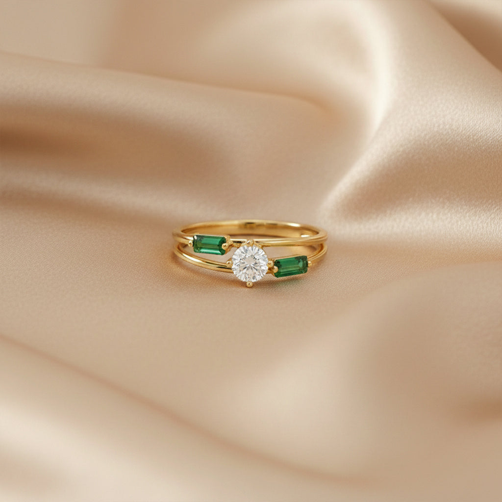 Gold ring with a diamond and emeralds on beige satin fabric
