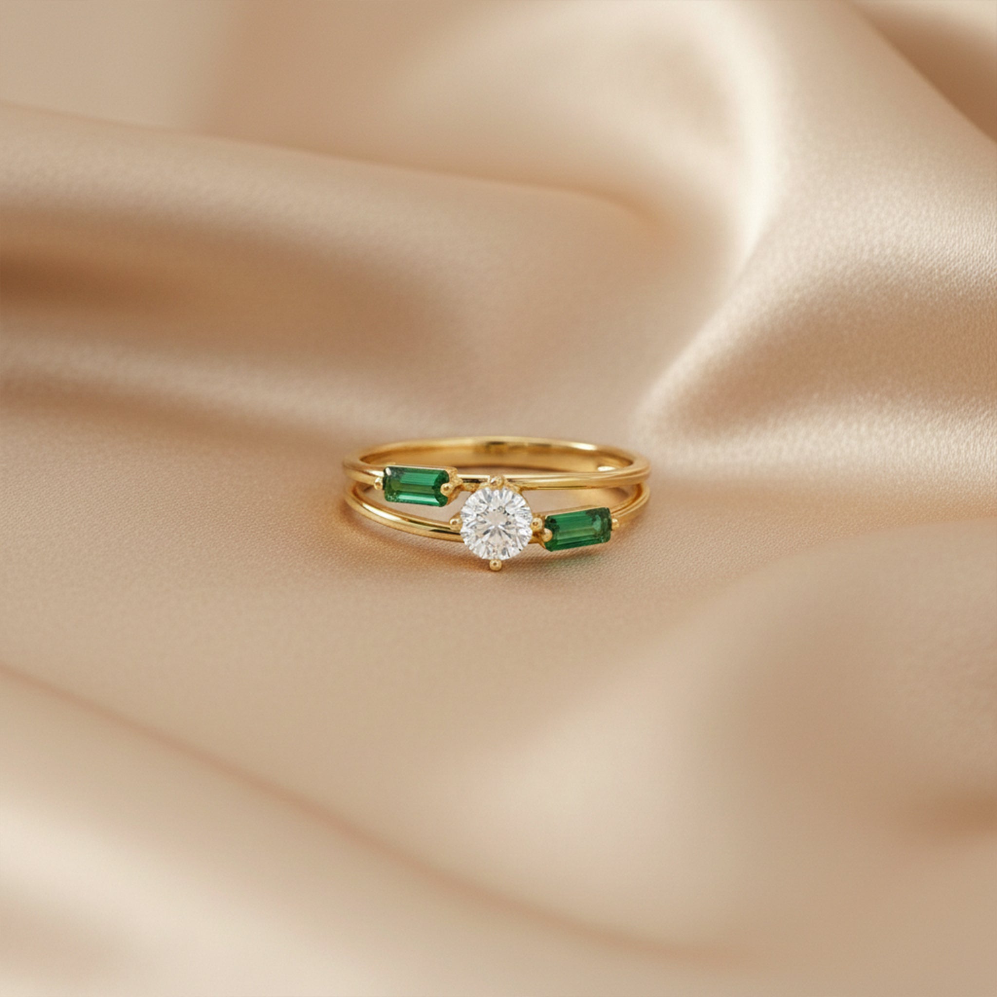 Gold ring with a diamond and emeralds on beige satin fabric