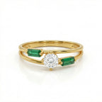Gold ring with a diamond and emerald stones on a white background
