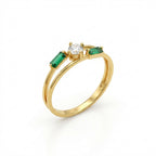 Gold ring with a central diamond and two emeralds on a white background
