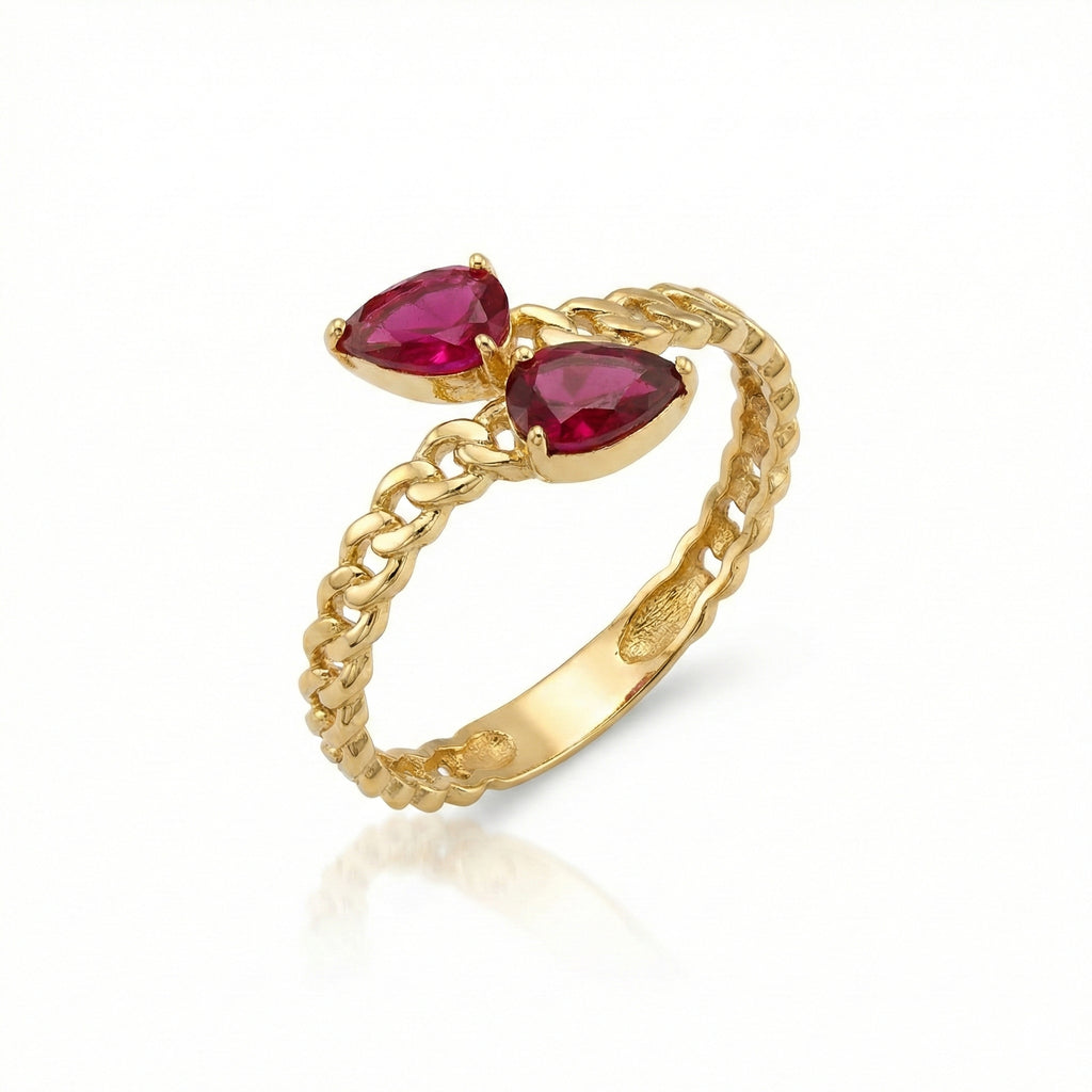 Gold ring with two pear-shaped red gemstones on a white background