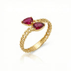 Gold ring with two pear-shaped red gemstones on a white background