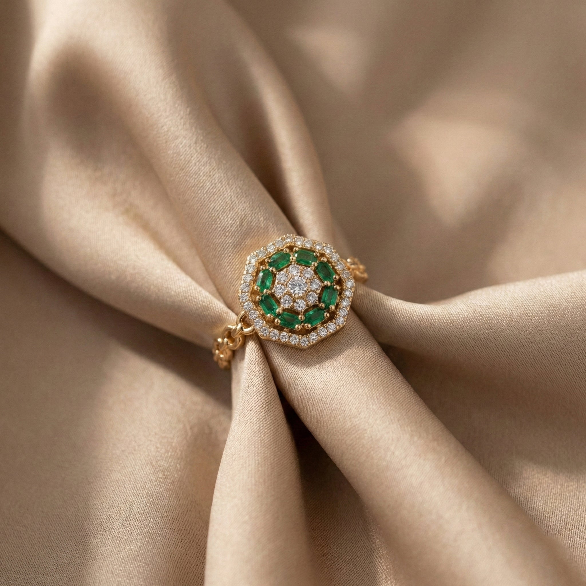 Gold ring with green gemstones on beige fabric